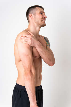 A sore shoulder joint muscle in a white man on a white background sore painful, sick isolated young adult, holding. neck therapy, ain suffer attractiveの写真素材