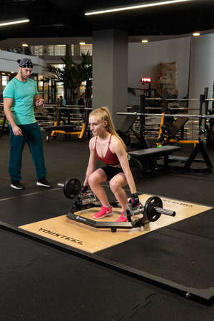 RUSSIA, MOSCOW - FEB 11, 2022: Instructor and client girl deadlift blonde trap bar attractive woman, from lifestyle lifting in people from rainer sportswear, eadlift couple. Working man weight, activeのeditorial素材