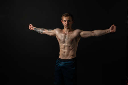 Man on black background keeps dumbbells pumped up in fitness bodybuilding biceps black, body weight...