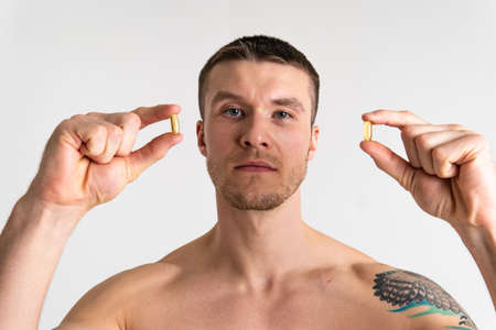 Fish oil is eaten by a man in the hands of vials and a glass bottle fish health medicine diet nutritional lifestyle, medication closeup. People white translucent, eat female giving dietingの写真素材