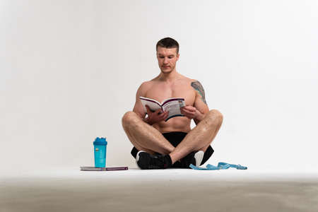 Bodybuilder reads the book on a white background isolated at the bottom of his head on his hands man muscle fitness background adult, happy Isolated gym, vision tanの写真素材