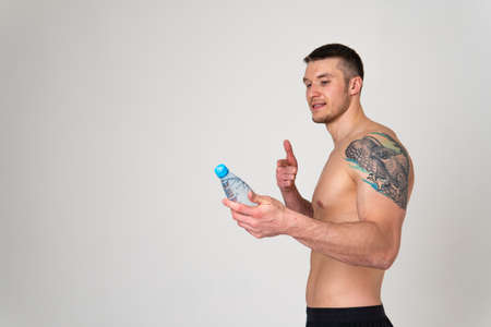 Male drink-water fitness is pumped with a towel on a white background isolated fit muscular training sport gym nutrition guy, break athletic. Strength perfect, powerful one muscleの写真素材