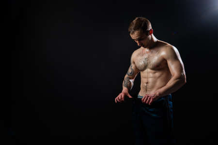 Man on black background keeps dumbbells pumped up in fitness active sport, body muscular strong...
