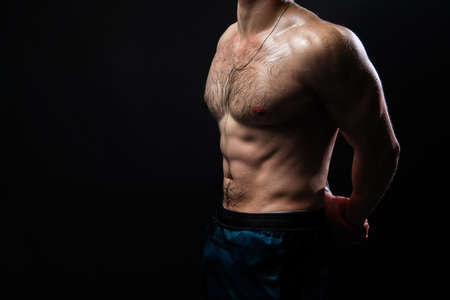 Man on black background keeps dumbbells pumped up in fitness biceps torso, athlete training workout...