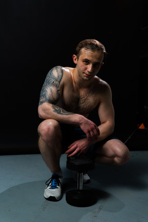 Man on black background keeps dumbbells pumped up in fitness bodybuilding chest torso, arm weight workout bodybuilder dumbbell, Attractive skin power, gym fitの写真素材