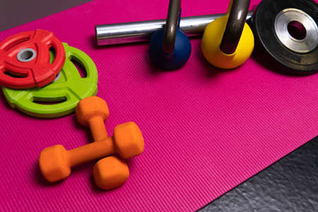 Dumbbells sport red rod weight yellow blue green steel, from fitness dumbbell in athletic for room towel, light lifting. Empty floor background, flatの写真素材