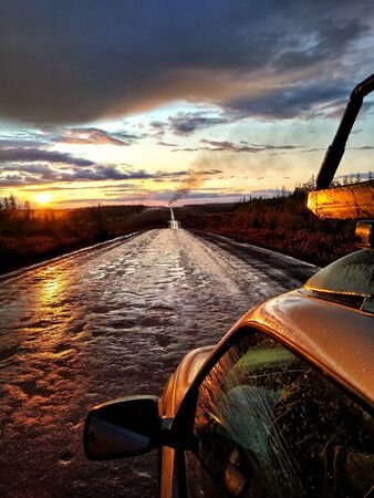 Traveling by car on a dirt country road to sunset after rainの写真素材