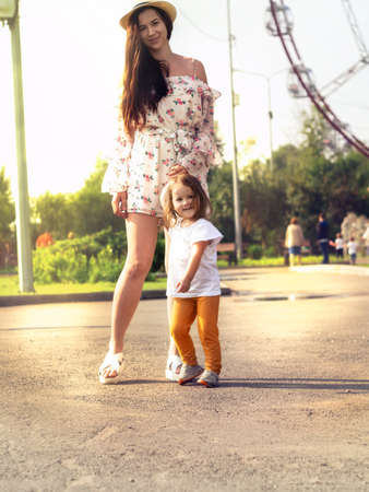 Vertical photo with a young mother walking with her child in a city park on a sunny summer or autumn dayの写真素材