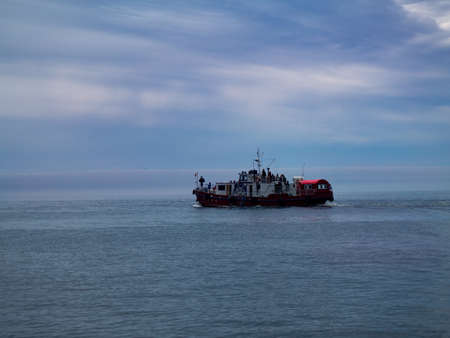 Photo of a ship against the backdrop of a calm sea and sky with cloudsの写真素材