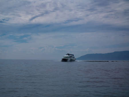 Photo of a ship against the backdrop of a calm sea and sky with cloudsの写真素材