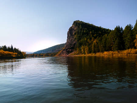The river of Siberia, a forest bank with hills and a rock is depicted. The image was taken in early autumn, on a sunny day.の写真素材