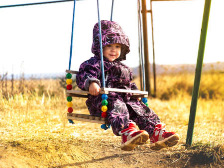 Bright colorful photo with a child on a swing in a sunny dayの写真素材