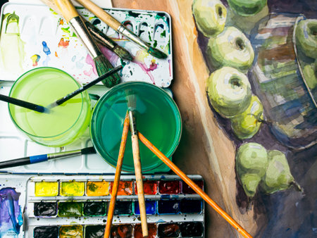 Paint brushes and watercolor paints on a wooden palette with applesの写真素材