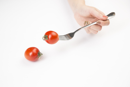 Red tomato gently in your hand on a white backgroundの写真素材