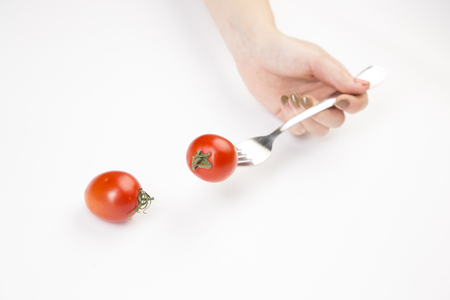 Red tomato gently in your hand on a white backgroundの写真素材
