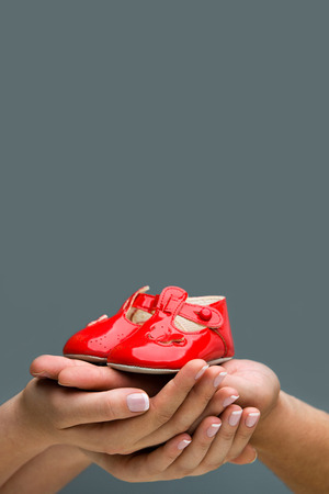 Parents Expecting a baby  Close-up of woman and her husband holding baby shoes in their hands  For poster の写真素材