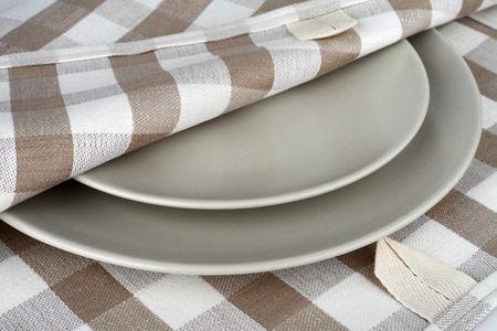 Towel in beige plaid and gray plates. Kitchen linen towel and plates.の写真素材