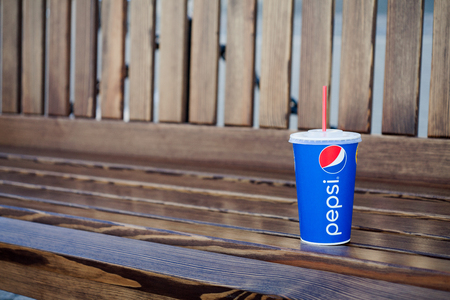 Minsk, Belarus, may 19, 2017: paper cup of Pepsi on a bench in the city. Pepsi is a carbonated soft drink produced PepsiCoのeditorial素材