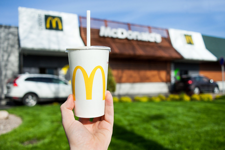 Minsk, Belarus, may 18, 2017: McDonald's soft drink paper cup in hand on blurry McDonald's Restaurant backgroundのeditorial素材