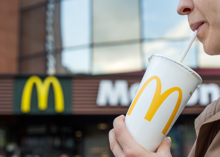 Minsk, Belarus, june 23, 2017: McDonald's soft drink. Woman drinks a drink in the background of the McDonald's restaurantのeditorial素材