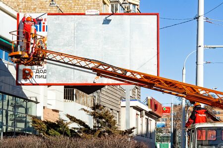 Minsk, Belarus, March 22, 2019: Worker change billboard. Advertising space in the city.のeditorial素材