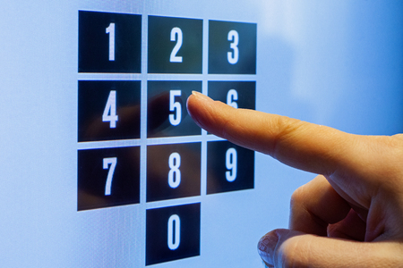 Female hand touching a screen with numbers. Dial passcode.