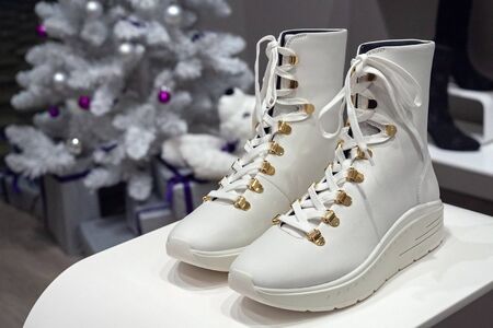 MINSK, BELARUS - December 13, 2019: Stuart Weizman women's high white boots on a shelf in a company...