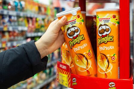 MINSK, BELARUS - December 19, 2019: A buyer buys Pringles chips at a supermarket. Hand hold a new tube of Pringles Potato Chips.のeditorial素材