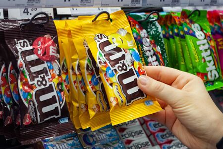 MINSK, BELARUS - December 19, 2019: Buyer buys candy M & M's. Hand holding with candies M & M's produced by Mars, Incorporated.のeditorial素材
