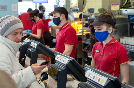 MINSK, BELARUS - April 27, 2020: Workers in medical masks serve customers at McDonald's restaurant...