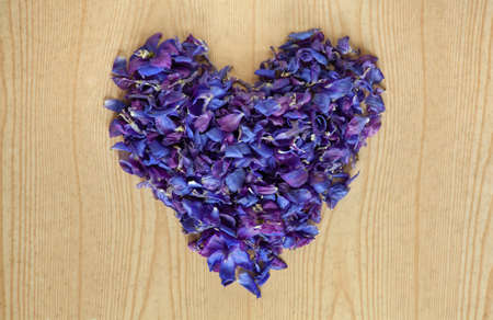 Vintage heart from flower petals on wooden table. Valentin day background