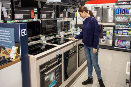 Woman chooses oven in store. Some freestanding cookers with oven and cooktop displayed in a store. Minsk, Belarus - March 2021のeditorial素材