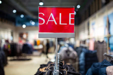 Red sale sign discount on clothing rack in modern shopping mall or department store with copy space. Retail shop promotional event, new product discount, or business marketing advertising conceptの写真素材