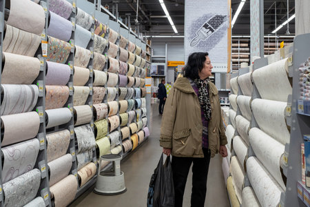 Samples of different wallpapers on store window racks. Woman choose wallpaper in hardware store. Minsk, Belarus, 2022のeditorial素材