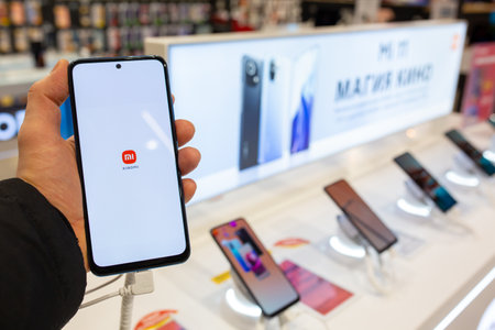 Smartphone with Xiaomi Logo on screen in hand. Customer choosing smartphone in mobile phones store....