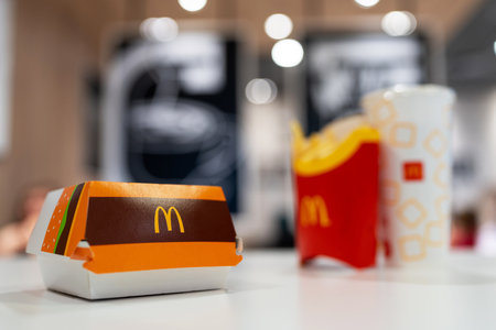 Big Mac Box with McDonald's logo, french fries and soft drink on table in McDonald's Restaurant....