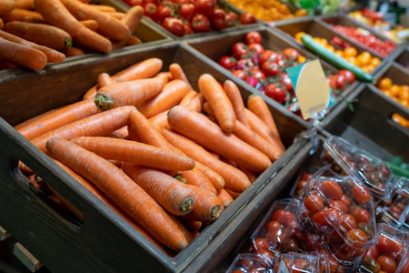 Carrots in a wooden box in the fruit and vegetable section of a grocery supermarket. Sale of carrots, selective focus. Vegetables in a supermarket close-upの写真素材