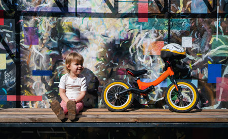 Active child. Sport for kids. Happy smiling child sitting after riding a balance bike against...