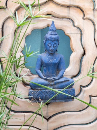 Buddha statue in meditation position on a lotus-shaped wooden background - design symbol peaceful.の写真素材