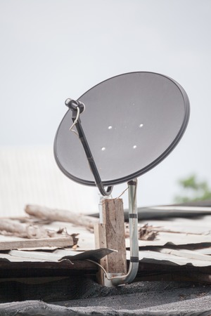 Black satellite dish on  on roofの写真素材