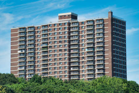 apartment building surrounded by trees on a sunny dayの写真素材