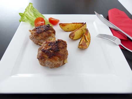Meatballs served with rosemary potatoes on square plate
