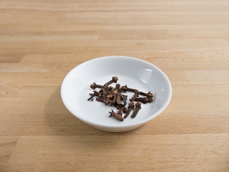 Cloves in a bowl on wood の写真素材