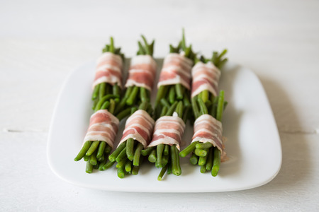 Beans in bacon on white plate