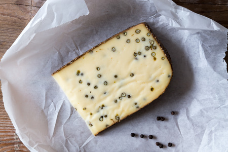 Pepper cheese and peppercorns on a wooden table