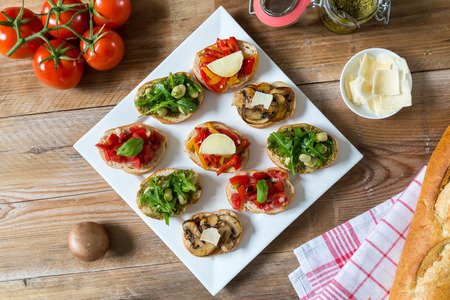 Bruschetta with beans and arugula, mushrooms, goat cheese on a wooden boardの写真素材