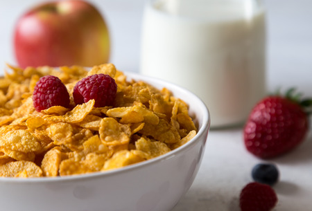 Cornflakes in a bowl with milk and fruits