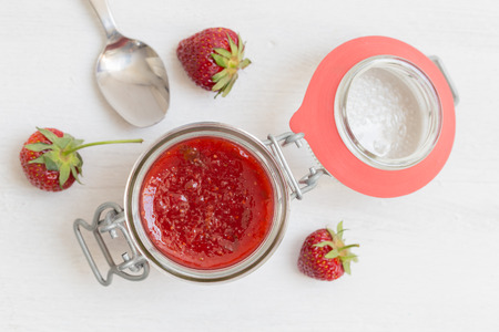 Strawberry jam in a jar on wood.