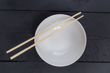 Bowl with chopsticks on a black wooden bird's eye view.の写真素材