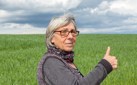 Senior Woman in the wind with thumbs up.の写真素材